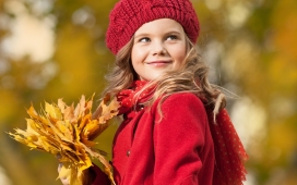 头戴针织毛线帽，身穿红色衣，手捧黄色枫叶的女孩