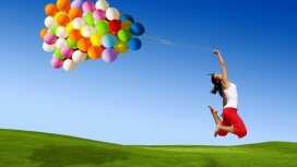 美丽的生命-绿色草坪上手拿五彩气球跳跃的女孩壁纸