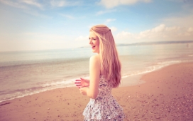站在沙滩旁的微笑金发女郎