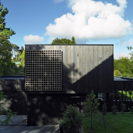 新西兰木格房屋-坐落在一个陡峭的斜坡处，整栋房屋外墙采用黑色染色木材，胶合板屏幕，光线可以透过格栅进入室内。里面住着一堆60多岁的夫妇，设计师故意不去模仿野生美丽复杂周边自然环境，而是假定一个安静低调的风格