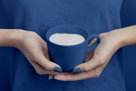 双手端蓝色咖啡牛奶的女子